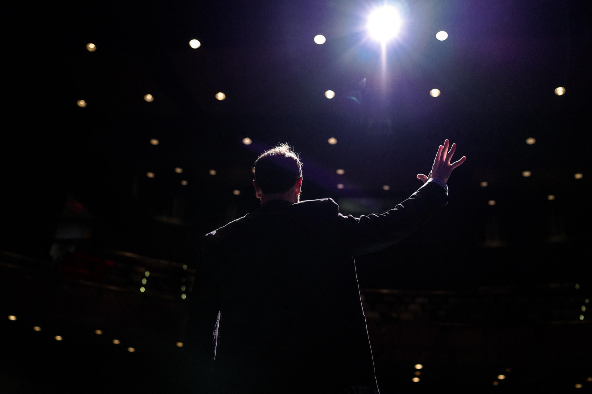 Peter Lazaroff on stage, addressing an audience under a spotlight